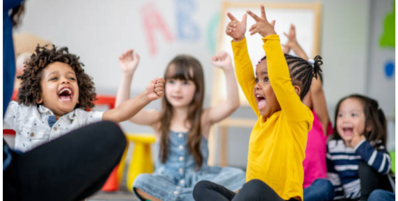 Preschoolers sitting in a circle smiling and playing